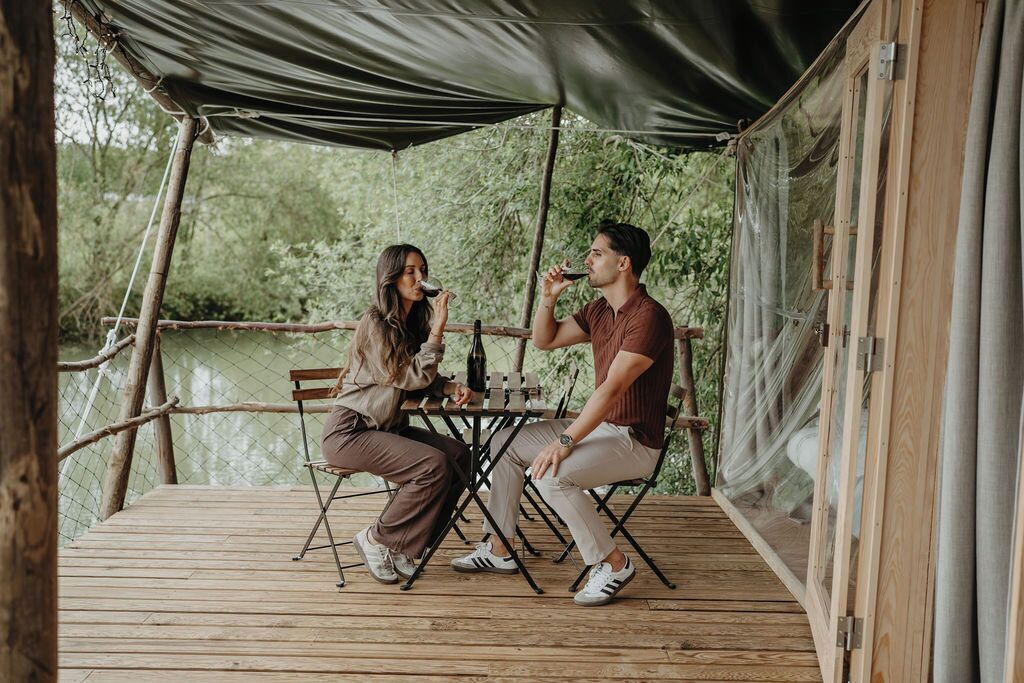 Une terrasse en bois avec une table et des chaises, entourée d’une clôture en bois et surmontée d’un auvent.