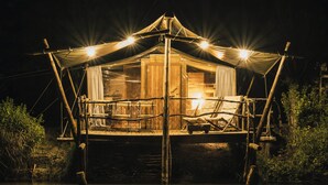 Een tentaccomodatie met een houten terras, een overdekte zithoek en een duidelijke ingang.