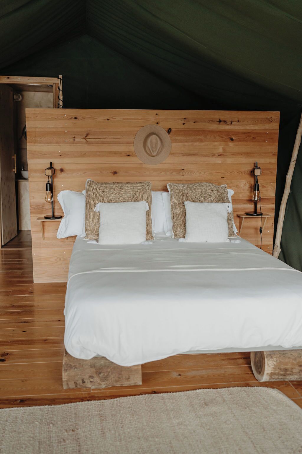 A bed with a wooden headboard, white bedding, and two bedside lamps.