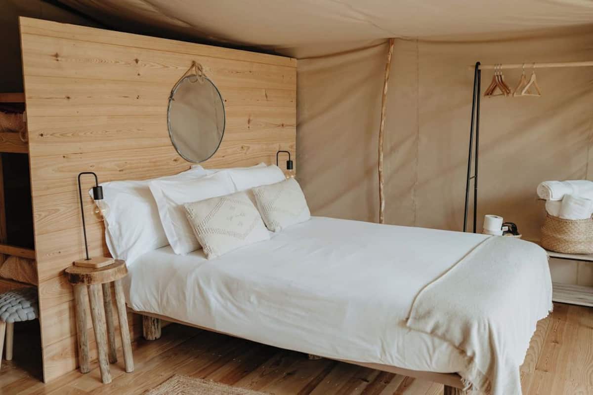 Un lit avec une tête de lit en bois, un miroir suspendu et une table de chevet avec une lampe.