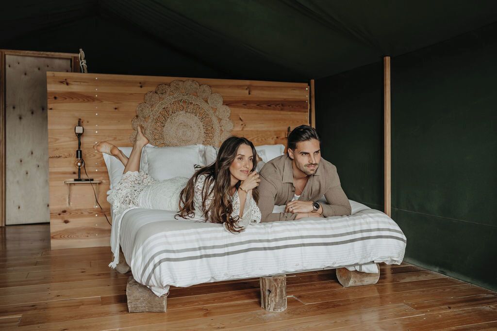 Ein hölzernes Bett mit rundem Kopfteil, eine Nachttischlampe und Holzboden.