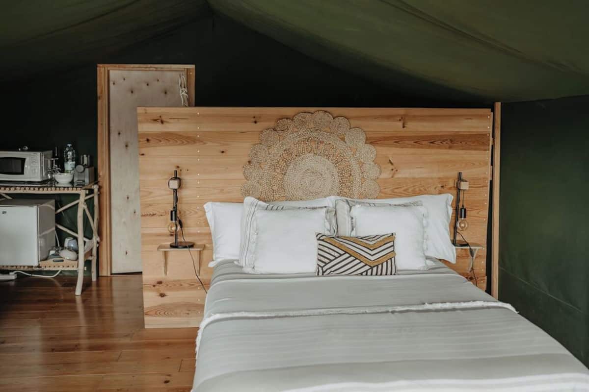 Une chambre à coucher avec une tête de lit en bois, un lit avec une literie blanche et une petite table de chevet avec une lampe.