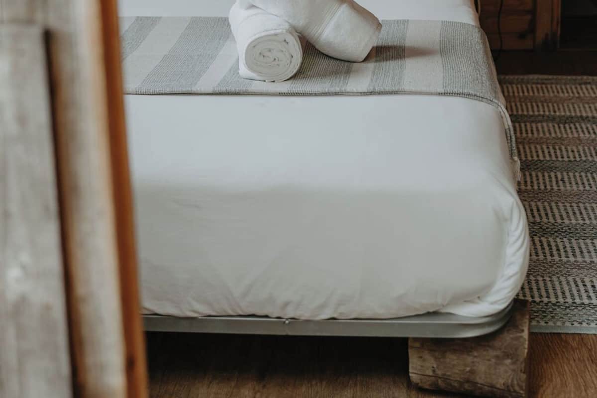 Une chambre de style cabane en bois, avec un lit, des oreillers et un luminaire suspendu.