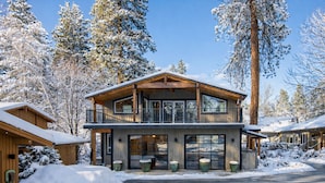 A two-story wooden cabin with a balcony, surrounded by snow-covered trees. - Riverside Loft Suite | Live Like a Local | Firepit (Leavenworth)