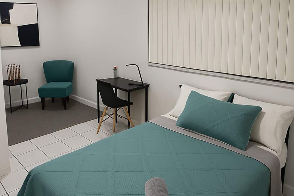 Ein ordentlich eingerichtetes Schlafzimmer mit Bett, Schreibtisch und Stuhl.