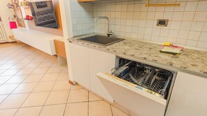 A kitchen with a sink, dishwasher, and tiled backsplash. - Sunset Sirmione Lake View (Sirmione)