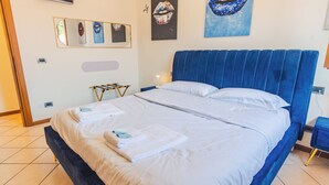 A hotel room with a large bed, a blue headboard, and artwork on the walls. - Sunset Sirmione Lake View (Sirmione)