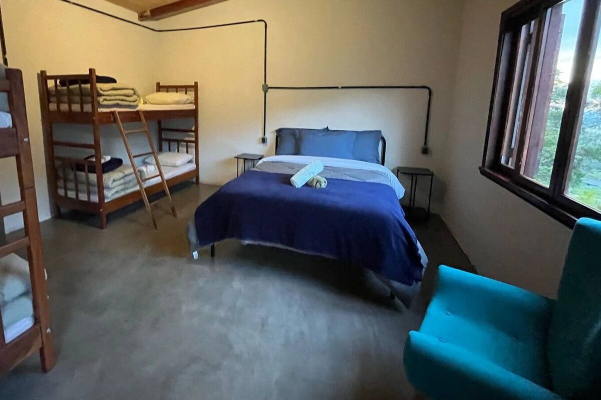Una habitación con literas, una cama individual, una silla y una ventana con vistas.