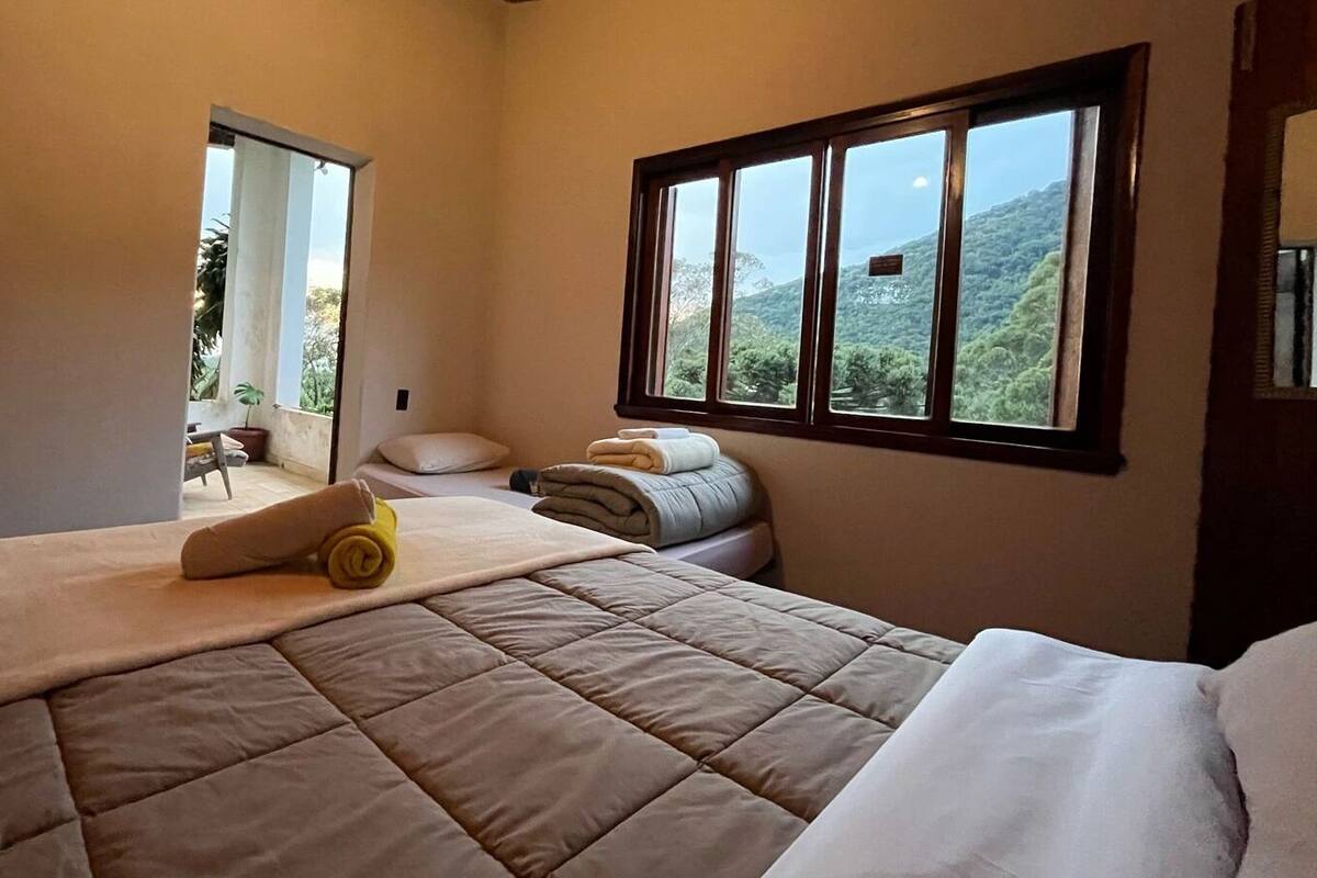 Un dormitorio con una cama grande, una ventana con vista a la montaña y una puerta que da a un espacio exterior.