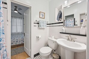 A bathroom with a toilet, sink, and shower curtain. - Charming 3-bedroom house with AC, WiFi in fantastic Hampton (Hampton)