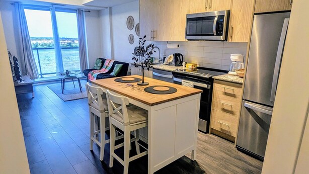 A modern kitchen with a central island, stainless steel appliances, and a view to the outside.