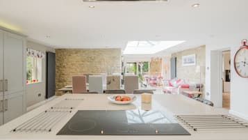 A modern kitchen with an island, stone wall, and dining area with chairs and a table.
