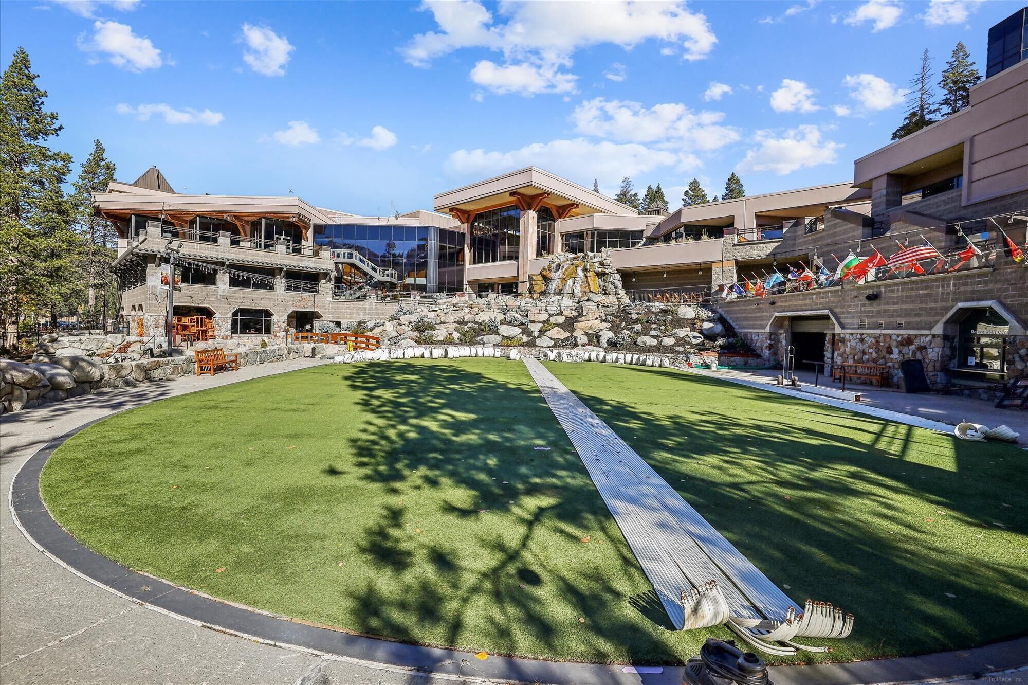 A resort with a central lawn, stone buildings, and a waterfall feature.