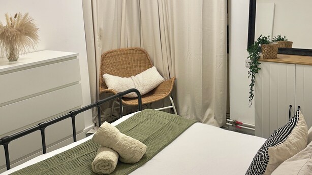 A bedroom with a bed, a chair, a mirror, and a radiator. - Spacious apartment in central London - 10-15 minutes from major attractions! (London)
