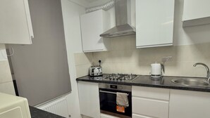 A modern kitchen with white cabinets, a gas stove, a built-in oven, and a stainless steel sink. - Spacious apartment in central London - 10-15 minutes from major attractions! (London)
