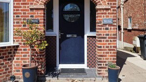 A brick house with a dark blue door, a small garden, and a sign reading "Pier Avenue." - The Waverley (Reydon)