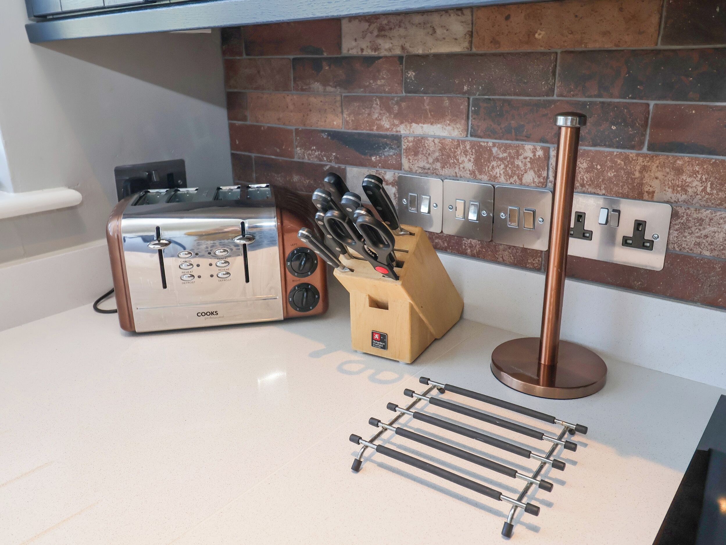 A kitchen counter with a toaster, a knife block, and a metal rack.