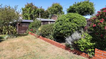 A garden with a brick wall, various plants, and a wooden structure.