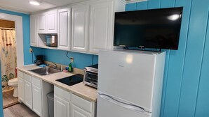 A compact kitchen with white cabinets, a built-in microwave, a toaster, and a refrigerator.