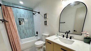 A modern bathroom with a bathtub, toilet, and vanity with a sink and mirror. - 2 king beds -2nd fl walk 2 beach #5 (norfolk)