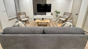 A modern living room with a sofa, two armchairs, a coffee table, a TV, and a decorative plant. - 2 king beds -2nd fl walk 2 beach #5 (norfolk)
