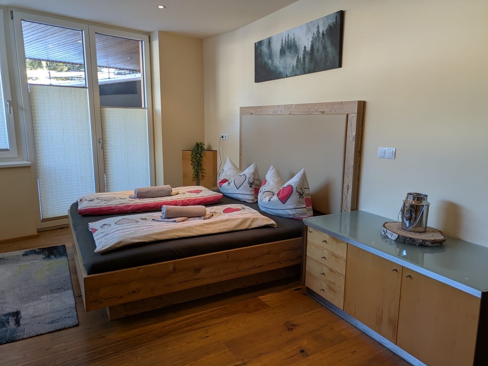 Un dormitorio con cama, mesita de noche, cómoda y un cuadro en la pared.