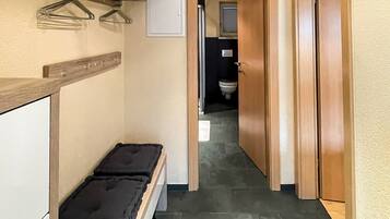 A hallway with a bench, wooden doors, and a tiled floor.