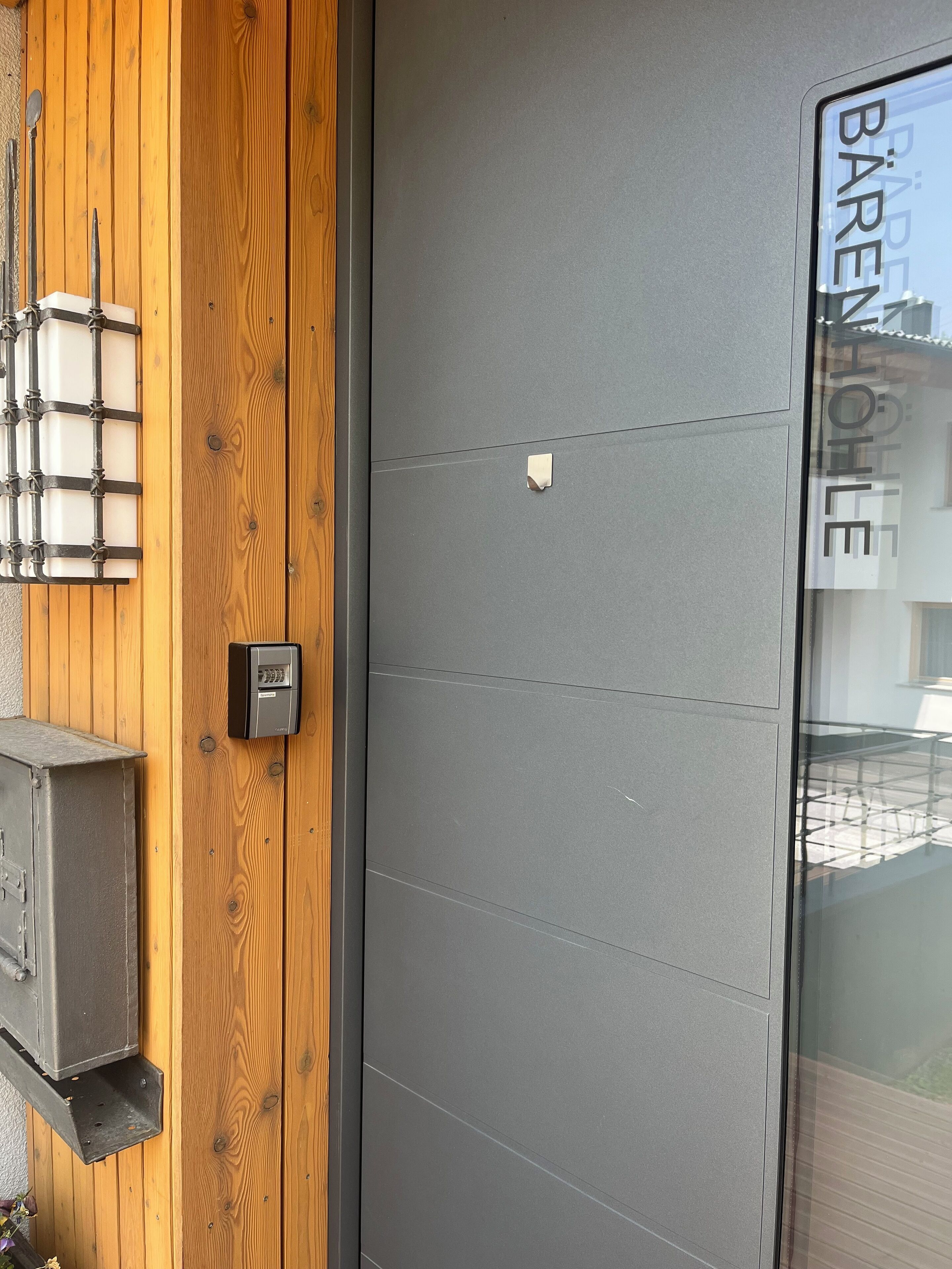 Fachada de edificio moderna con panel de madera y puerta gris.