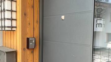 Fachada de edificio moderna con panel de madera y puerta gris.