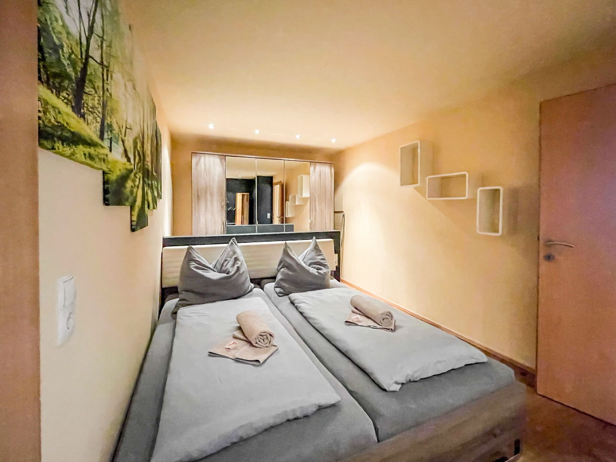 Una habitación de hotel con dos camas, un espejo grande y un cuadro en la pared.