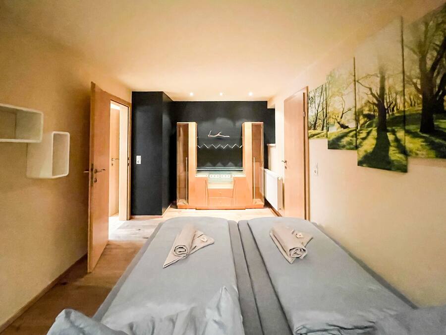 Habitación de hotel con dos camas, una kitchenette pequeña y vistas a un bosque.