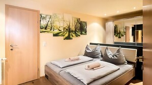 A bedroom with a bed, a door, a wall-mounted artwork, and a mirror. - Apartment Waldnah (Fließ)