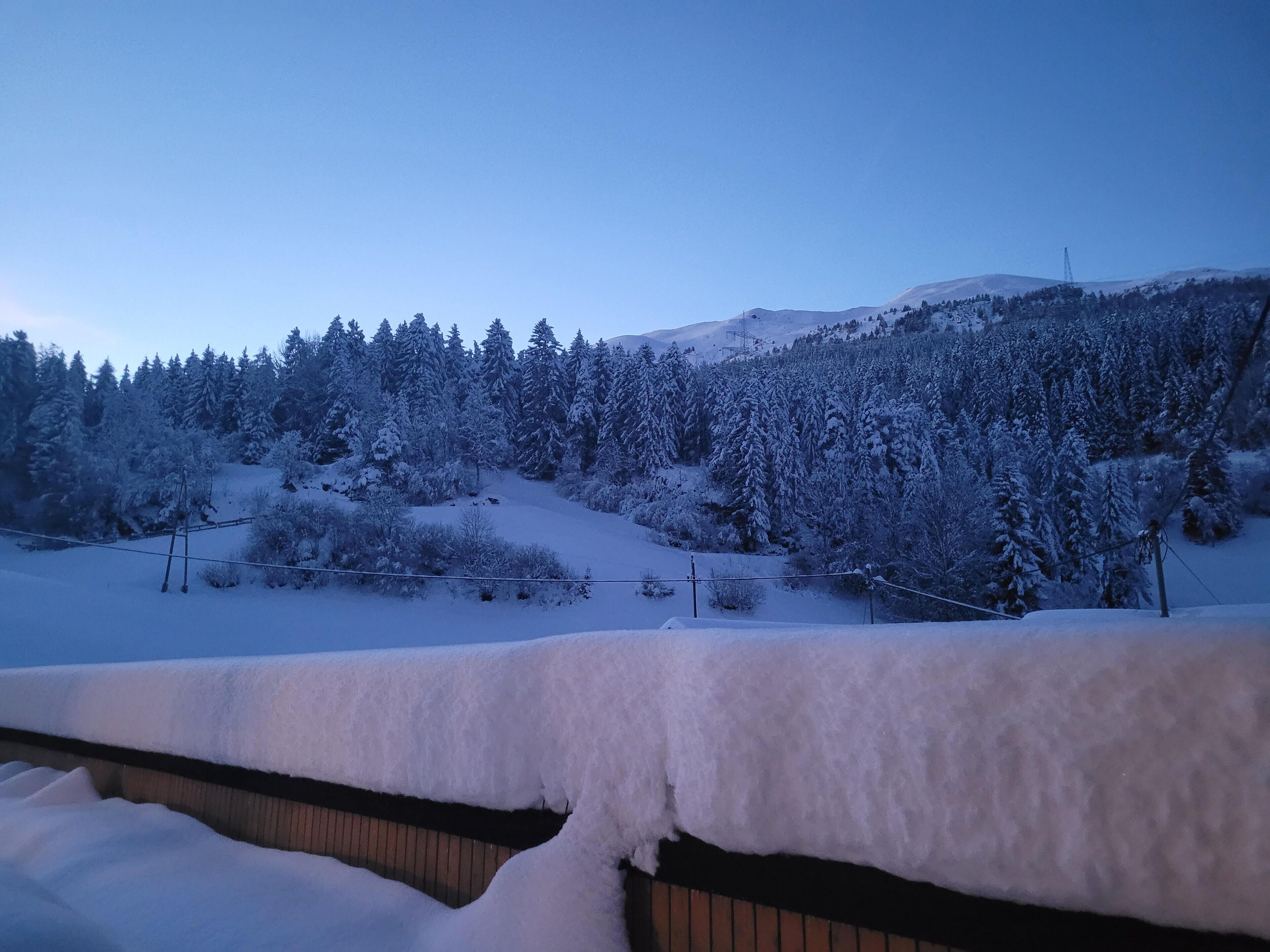 Un paysage enneigé avec une colline boisée et un ciel dégagé.