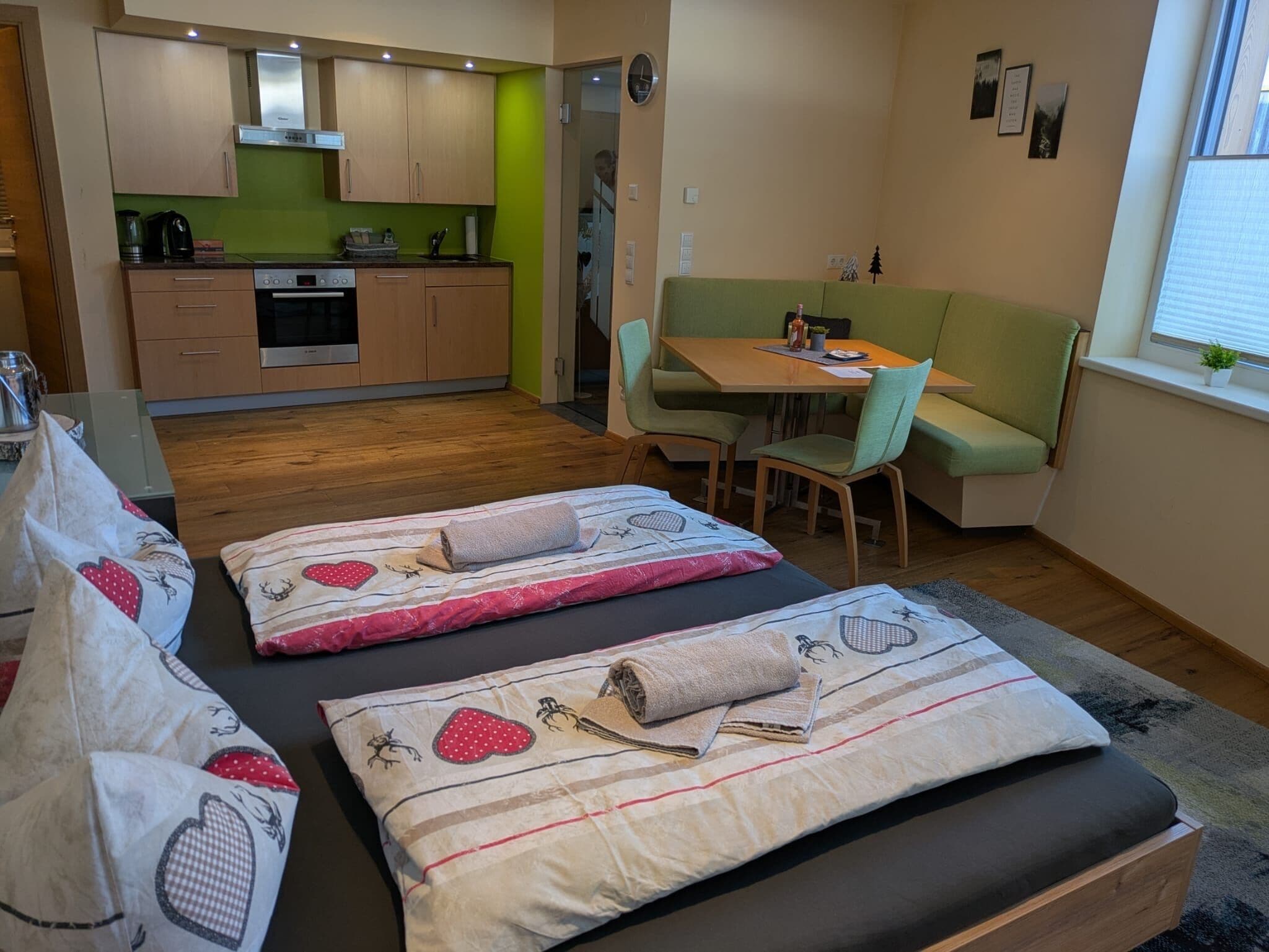 Un espacio habitable compacto con kitchenette, comedor y cama con almohadones decorativos.