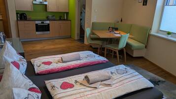 Un espacio habitable compacto con kitchenette, comedor y cama con almohadones decorativos.