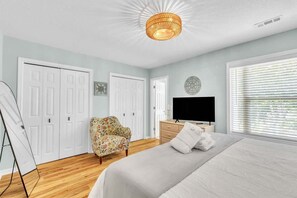 Quarto com cama, televisão, cadeira e guarda-roupa.