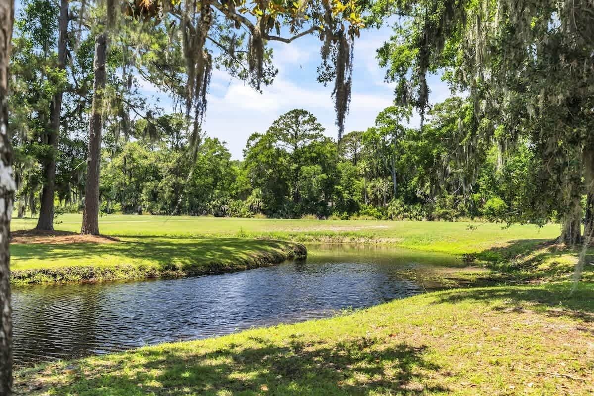 A serene outdoor setting with a pond, trees, and a grassy area.