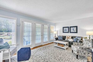 A living room with a sofa, armchairs, a coffee table, and a patterned rug.