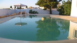 A swimming pool with a white wall, a tree, and a patio area with chairs and an umbrella. - Beautiful property in southern Portugal (Algarve) near Estômbar golf course (Unknown)