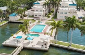 Un complexe hôtelier doté d’une piscine, de palmiers et d’un quai.