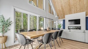 Un intérieur moderne avec une table à manger en bois, des chaises noires, un canapé et un téléviseur.