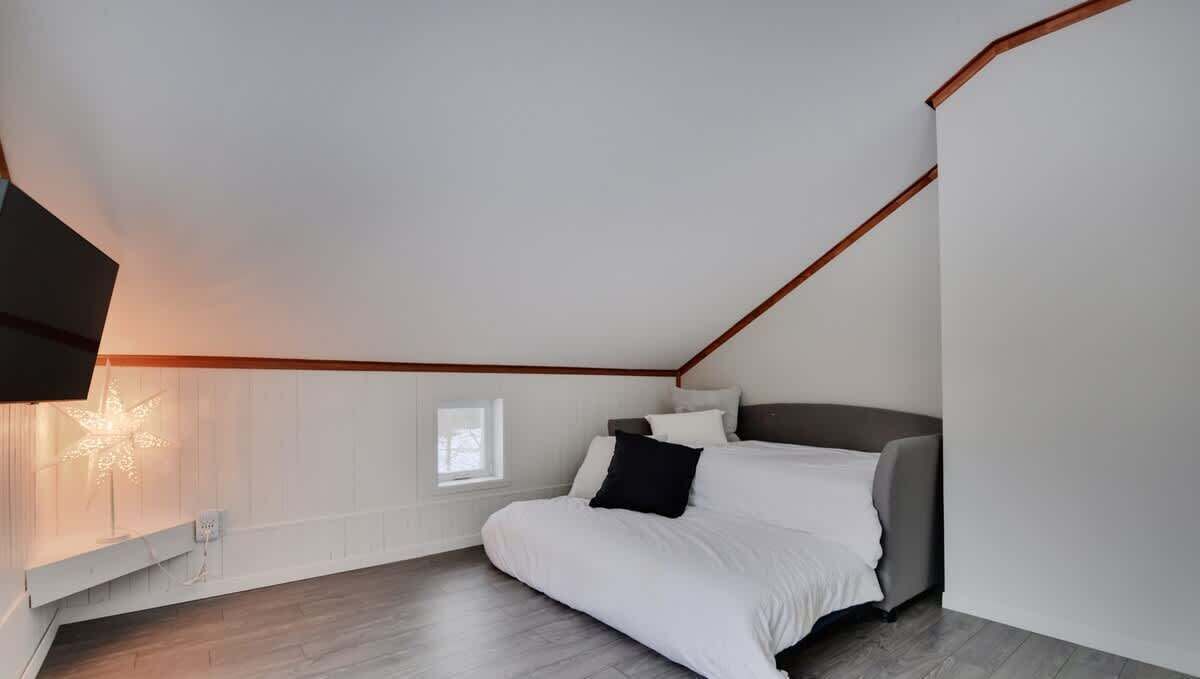 Ein Schlafzimmer mit einem Bett, einem Nachttisch, einer Wandleuchte und einem Fenster.