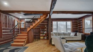 Un intérieur en bois avec un escalier, un canapé et une bibliothèque.