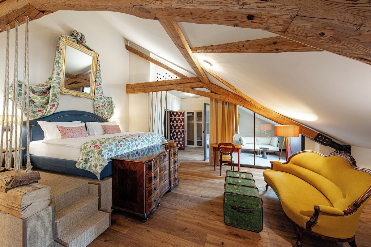 A bedroom with a bed, dresser, mirror, and a yellow armchair.