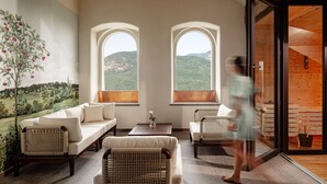 A room with a sofa, chairs, and a table. There are two windows with a view of hills. - Castel Sallegg Suites Adults only (Caldaro Sulla Strada del Vino)