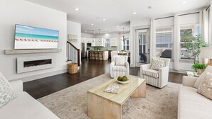A modern living room with a fireplace, a dining area, and a kitchen.