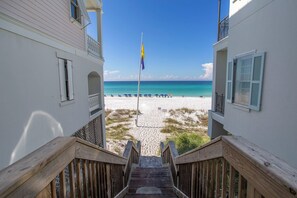 A wooden staircase leading to a beach with a flagpole and umbrellas. - Turtle Cove - Villas of Frangista, Private Pool, Golf Cart! (Miramar Beach)