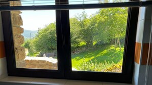 Un baño con un ventanal grande con vistas a un paisaje verde.