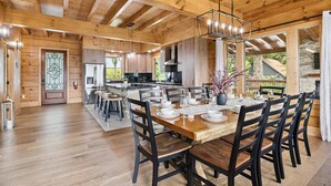 A spacious wooden dining area with a large table set for six, surrounded by dark wooden chairs.