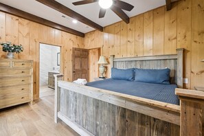 A bedroom with a wooden headboard, a wooden dresser, and a nightstand with a lamp. - Brand New Luxury Mountain Scape Swimming Pool Air Hockey Pool Table 3 Fire Place (Gatlinburg)
